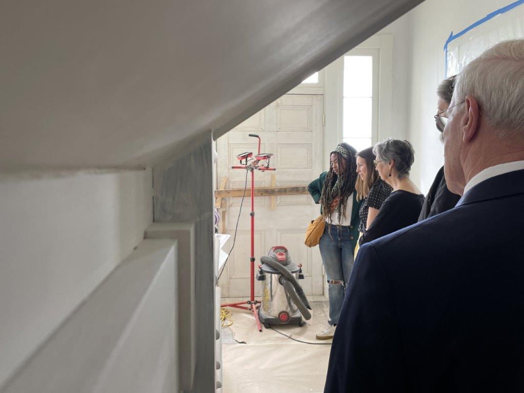 A group of five people in a hallway looking at areas of ongoing restoration work.