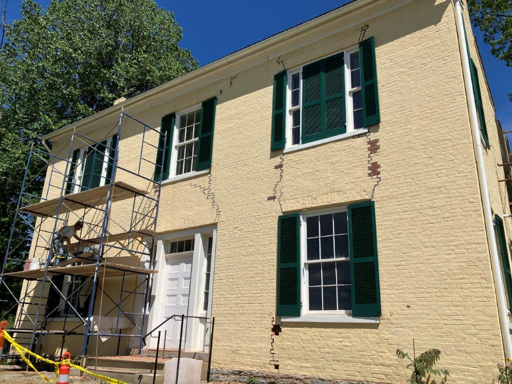 The yellow brick Harriett Beecher Stowe house with scaffolding and someone working on the left side.