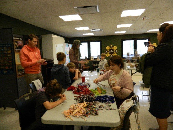 A group of people sitting around a plastic table working on crafts.