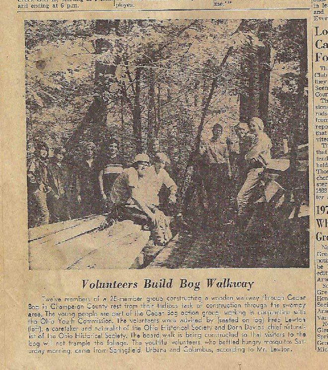 Old newspaper article with a picture of volunteers at Cedar Bog. The text says, " Twelve members of a 25-member group constructing a wooden walkway through Cedar Bog in Champaign Country rest from their tedious task of construction through the swampy area. The young people are part of the Cedar Bog action group working with the Ohio Youth Commision. The volunteers were advised by Fred Lewton, a caretaker and naturalist of the Ohio Historical Society and Dorn Davids, chief naturalist of the Ohio Historical Society. The board walk is being constructed so that visitors to the bog will not trample the foliage. The youthful volunteers, who battled hungry mosquitos Saturday morning came from Springfield, Urbana and Columbus, according to Mr. Lewton.