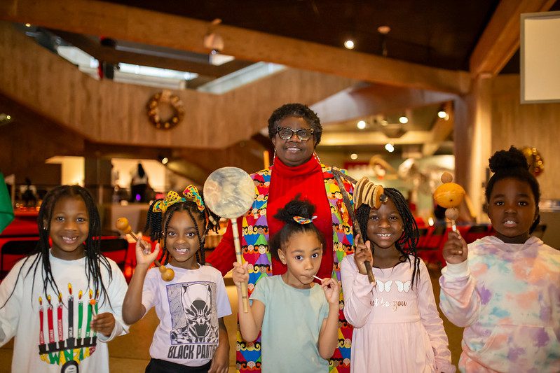 Image of an African American woman and 5 African American children holding instruments.