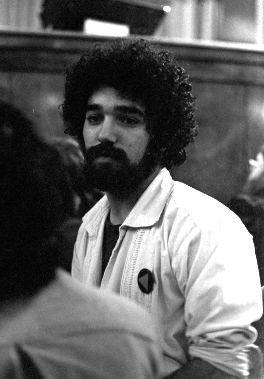 Black and white photo of a protester wearing a "pink" pride triangle pin