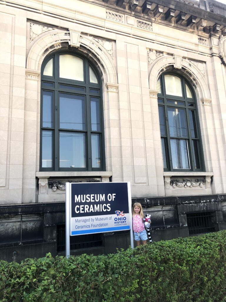 Small Child standing by the welcome sign to the Museum of Ceramics.