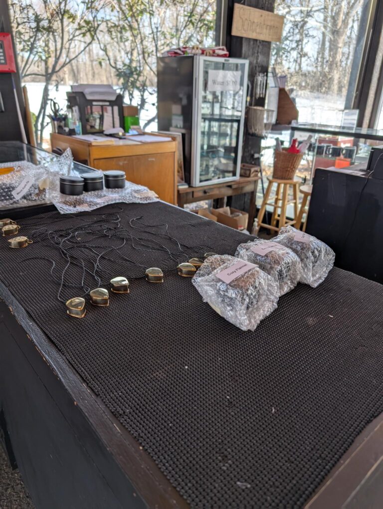 Table with some necklaces, and bubble wrapped packages on it.