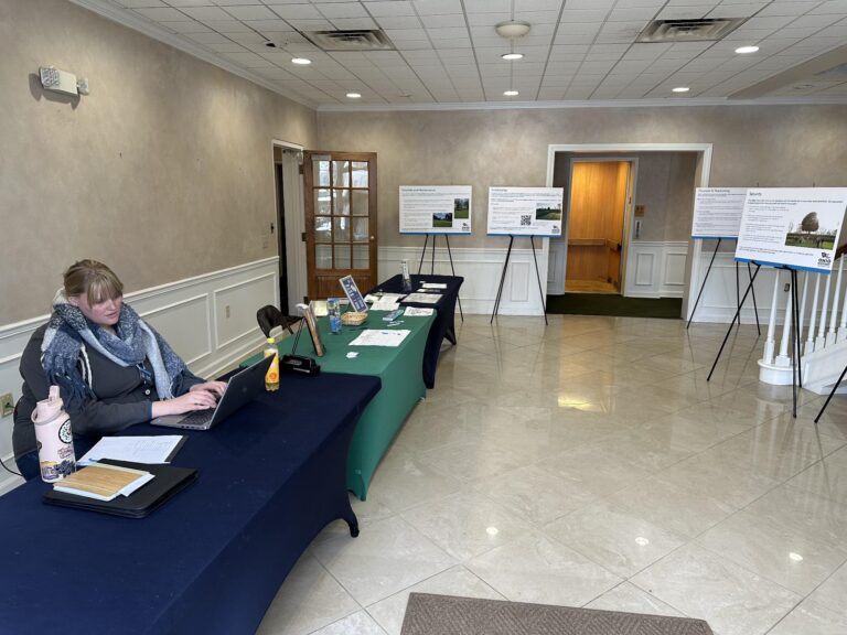 Interior of Building with three tables with information pamphlets down the left side. The right side has signs displayed on stands.